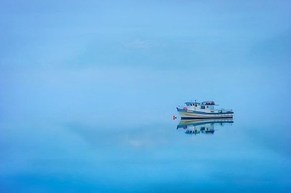 An Alaskan fishing boat floats into mist on still water