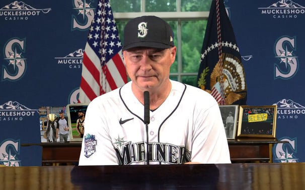 A morose Mariners Manager Scott Servais giving an announcement from a press conference desk 